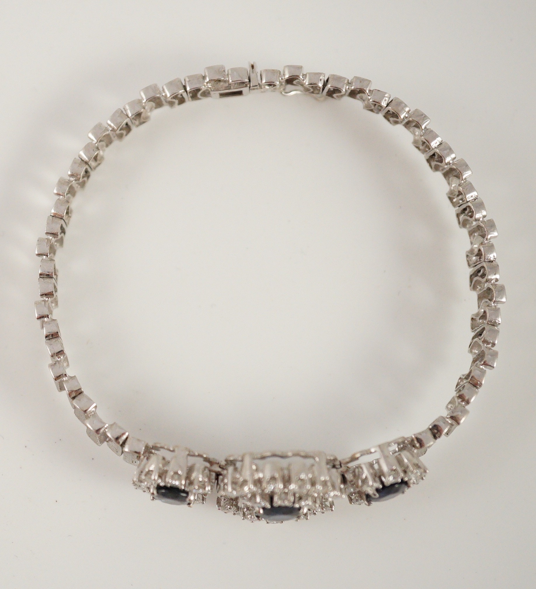 A mid to late 20th century textured 18k white gold, sapphire, round and baguette cut diamond set triple oval cluster bracelet